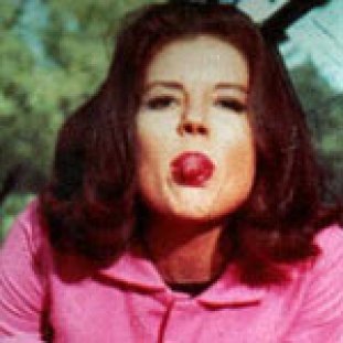 a young woman with dark hair and pale skin poking her tongue out at the photographer