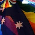 a silhouetted figure holding two flags - the australian flag and the rainbow flag