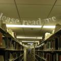 Library shelves with banners reading "Please read me" strung between them.