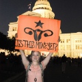 A woman standing in front of the US Capitol building holds up a sign displaying a stylised uterus and reading 'Is this mine yet?'
