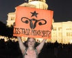 A woman standing in front of the US Capitol building holds up a sign displaying a stylised uterus and reading 'Is this mine yet?'