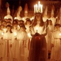 Group of girls holding candles, one at the front wearing a candle crown.