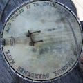 A well worn banjo body with faded rainbow text around the edge