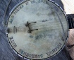 A well worn banjo body with faded rainbow text around the edge