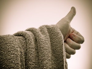 Photograph of a towel draped over an arm, with a thumb up to hitch a ride