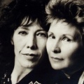 A close-up portrait of two middle-aged pale-skinned women, their faces close and touching