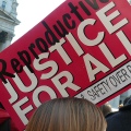Photo of banner at a rally, banner reads REPRODUCTIVE JUSTICE FOR ALL