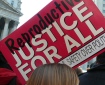 Photo of banner at a rally, banner reads REPRODUCTIVE JUSTICE FOR ALL